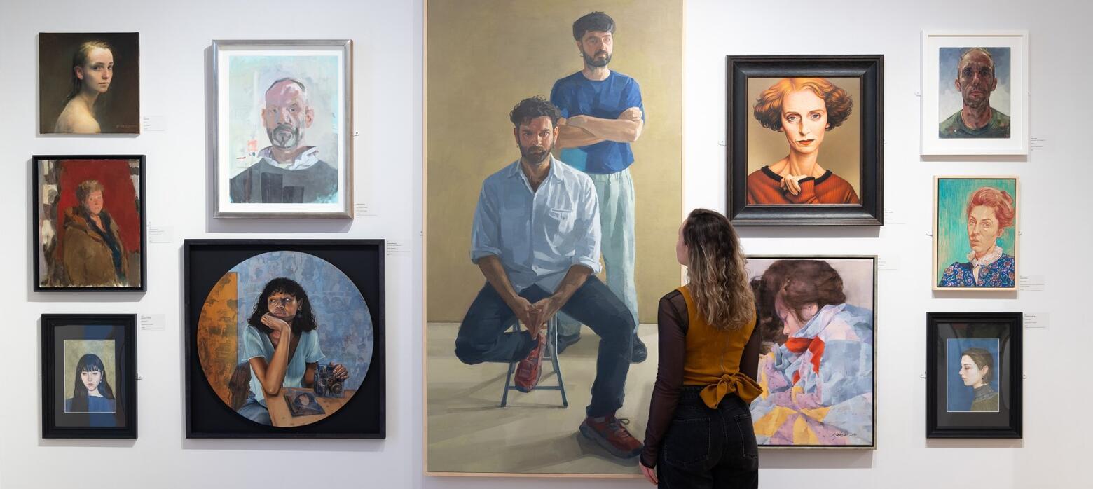 Woman admiring portraits in annual exhibition