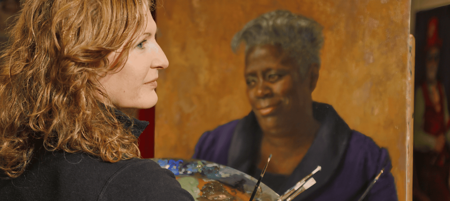 image of a woman with curly dark blonde hair in front of an easel 