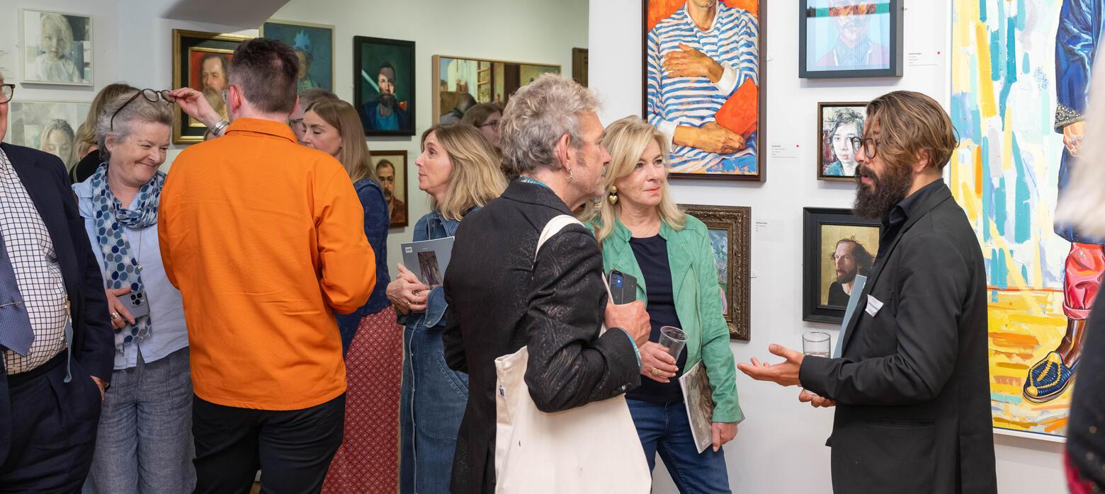 People gathered talking around paintings in RP 2024 Annual Exhibition