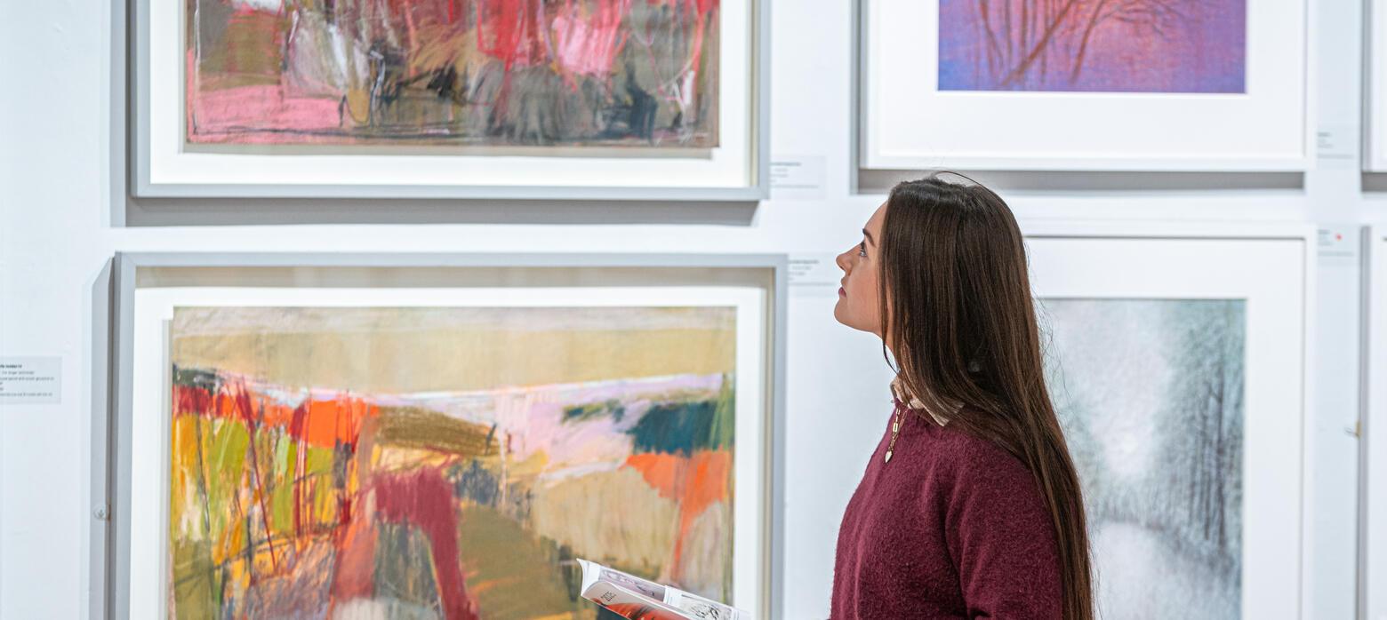 Girl in purple jumper standing in front of abstract artworks