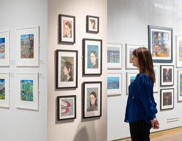 Photo of Phoebe Codling in front of paintings in the West Gallery