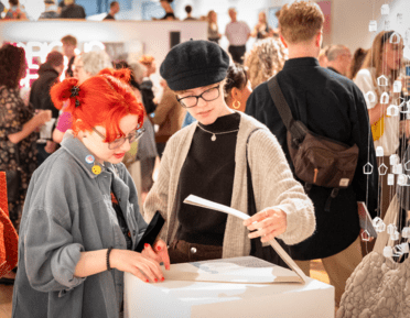 2 visitors looking at art on a table