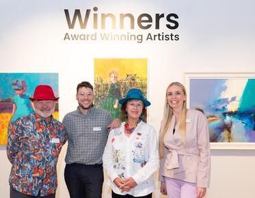 four people in front of paintings at the winners exhibition