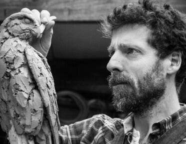 Photo of man craving a bird sculpture