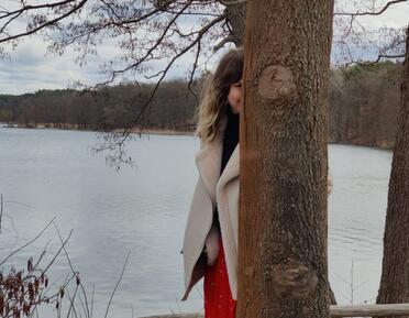 Artist Elisha Enfield stands behind tree