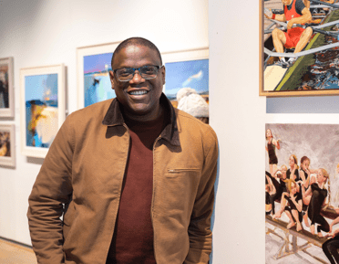 Adebanji Alade, first black president of the ROI stands next to his artwork at Mall Galleries